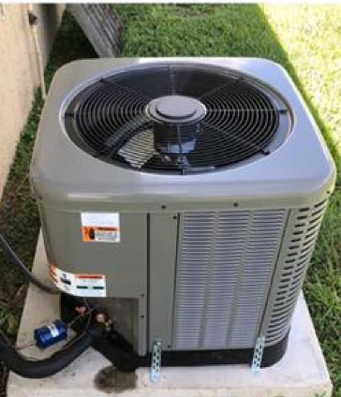 Newly installed condenser on a concrete pad with hurricane tie-downs.